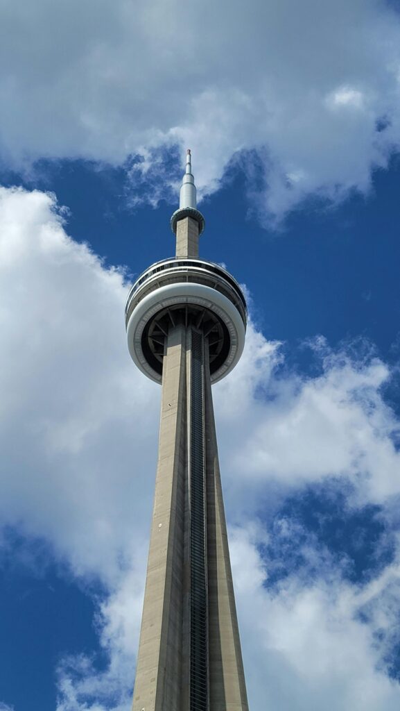 CN Tower in Toronto rising into a bright blue sky with scattered white clouds