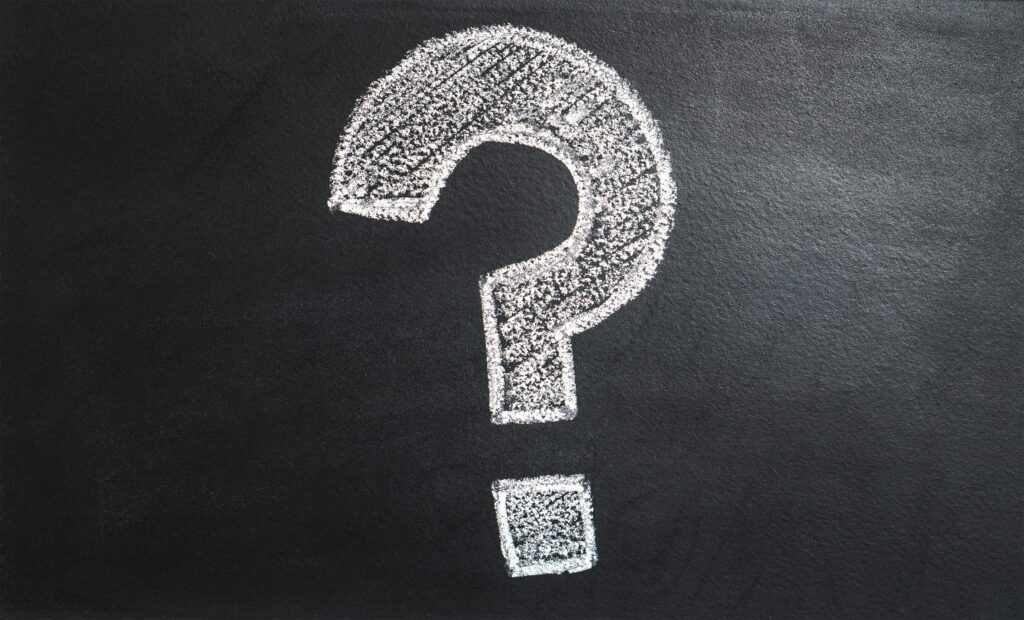 White chalk-drawn question mark on a blackboard background symbolizing curiosity, uncertainty, and inquiry