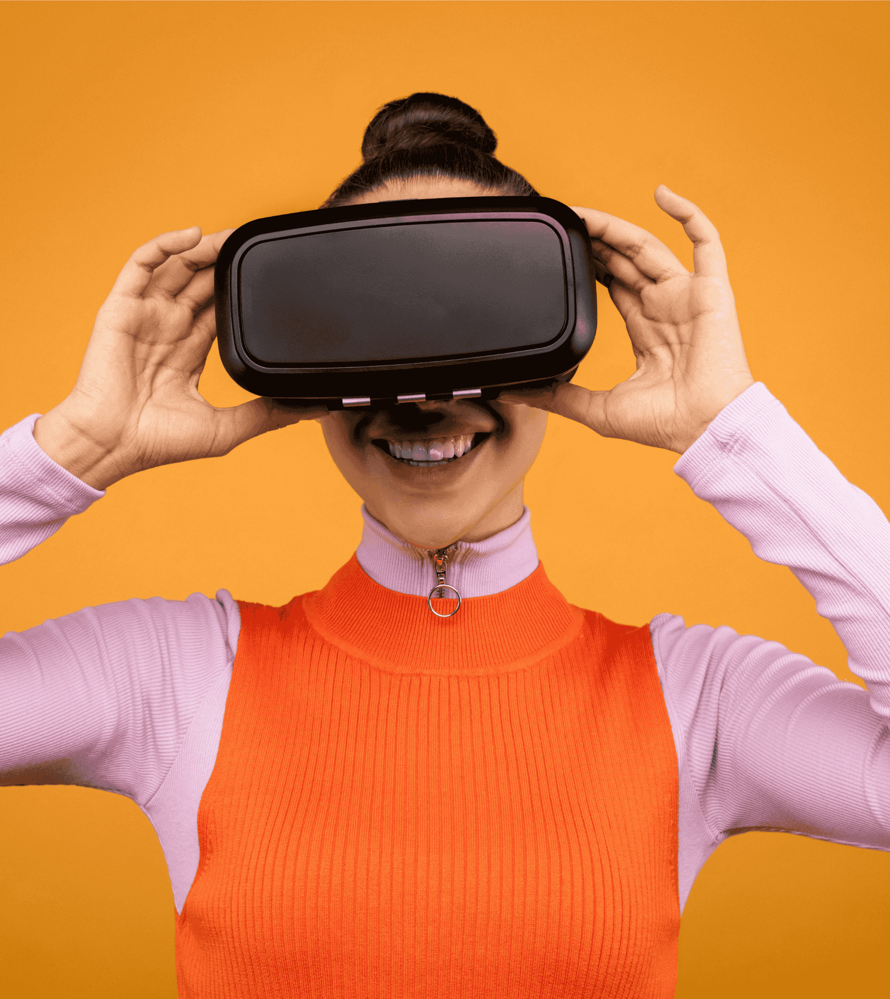Woman smiling while using virtual reality headset against an orange background.