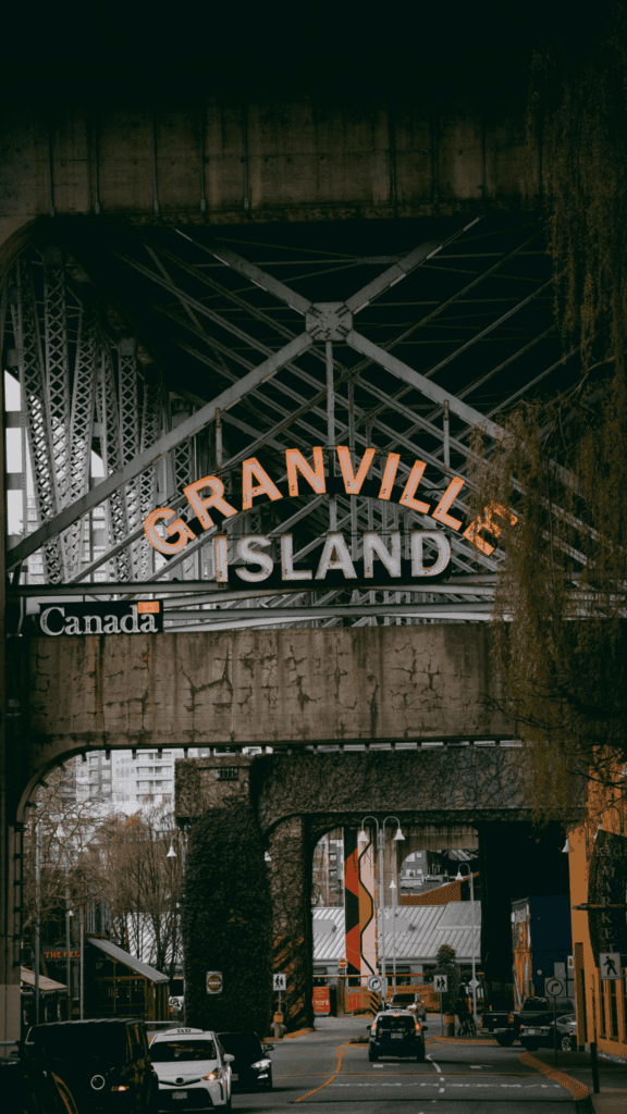 Granville Island entrance sign under the Granville Street Bridge in Vancouver, Canada with cars driving below