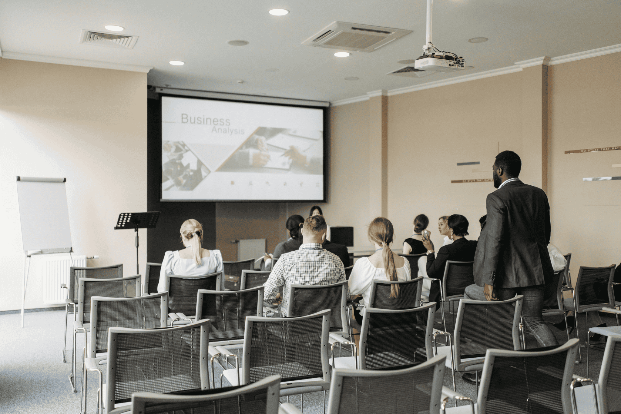 Business professionals attending a presentation on business analysis in a modern conference room.