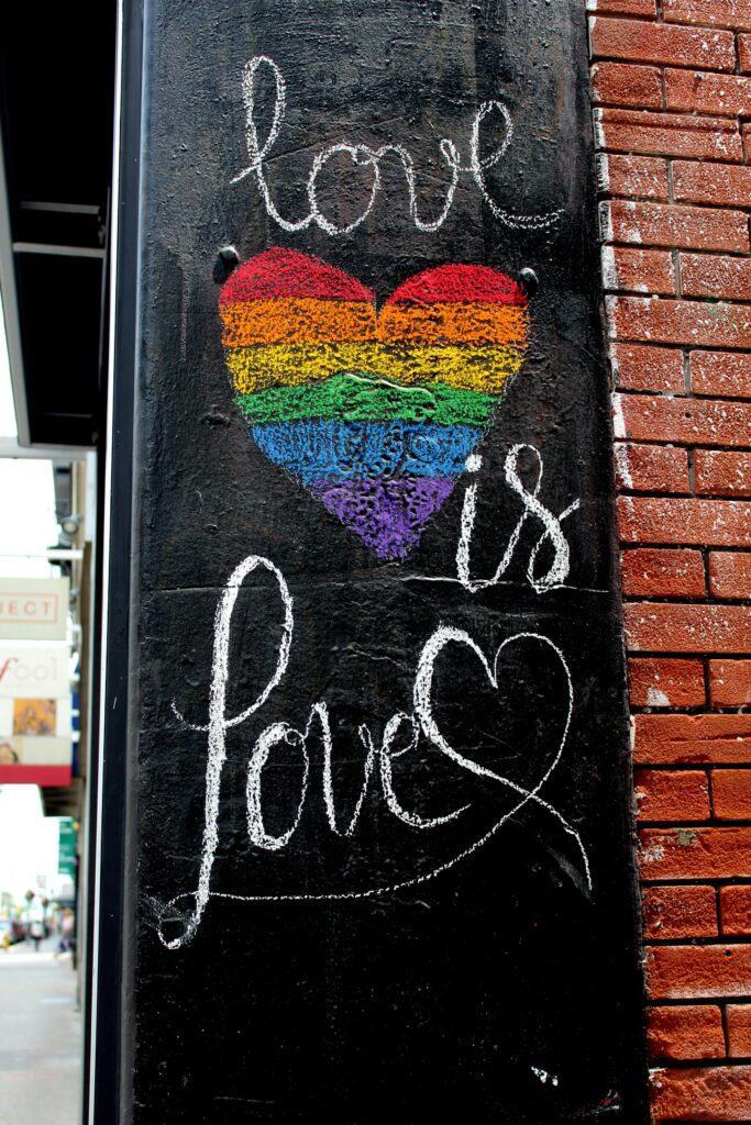 Street art with a rainbow heart and the words love is love promoting LGBTQ+ pride and inclusivity.
