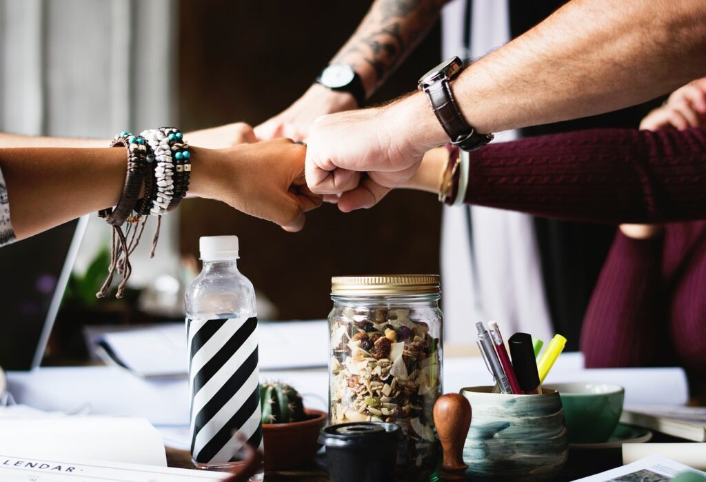 Several people join their fists together in a gesture of teamwork and unity