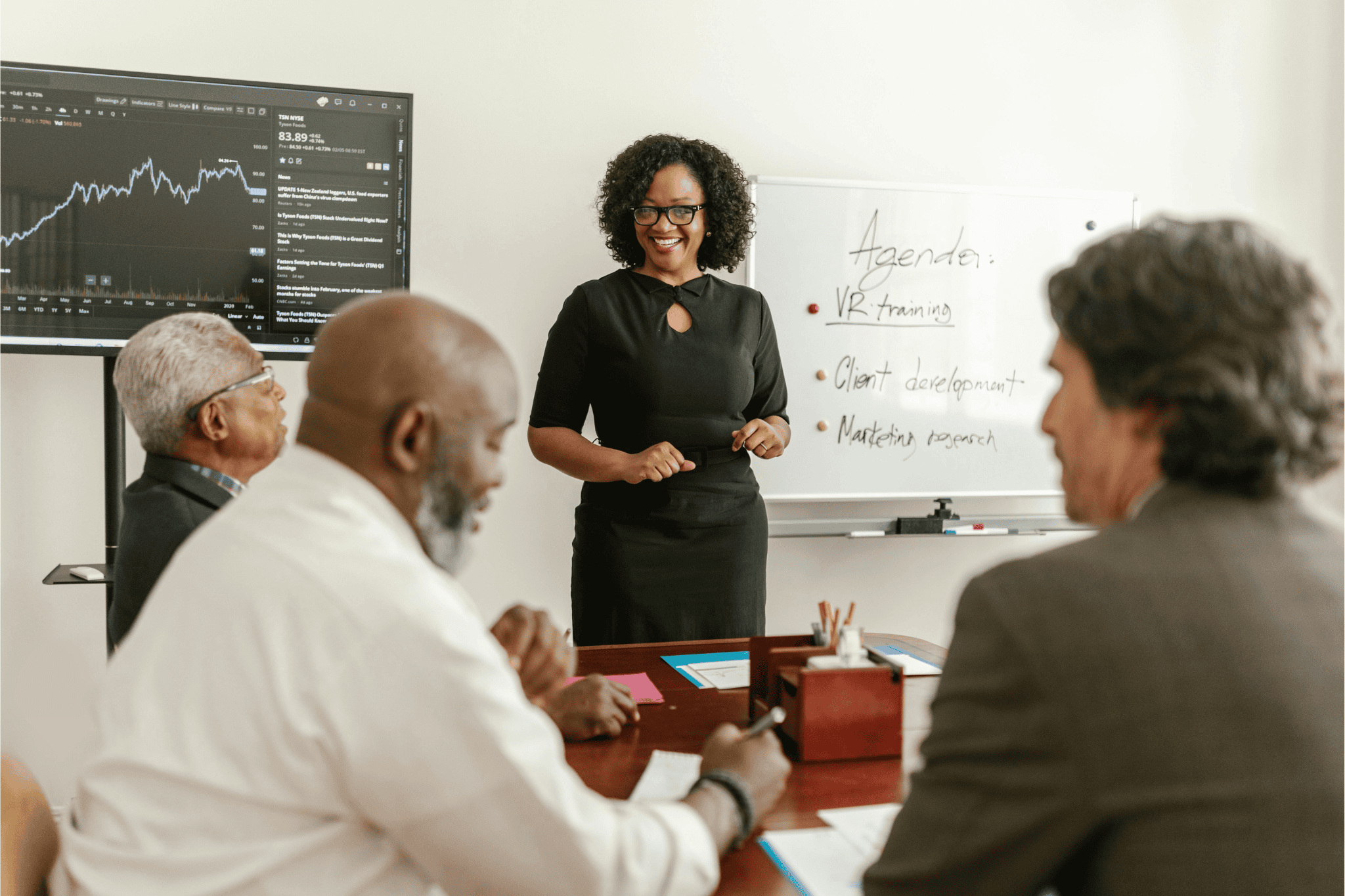 Business meeting with a woman presenting at a whiteboard to colleagues.