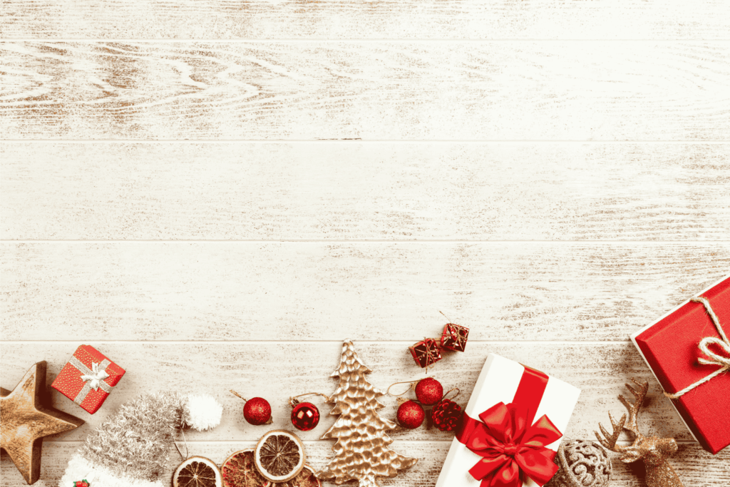 Christmas decorations and gift boxes with red and gold ornaments on a wooden background.
