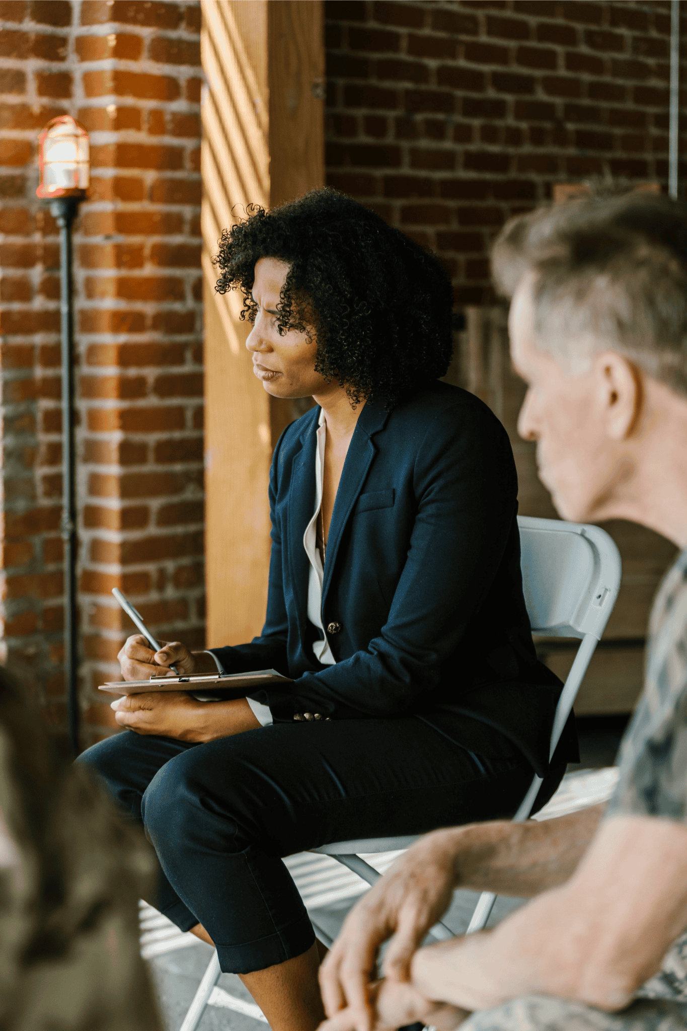 Woman in a business suit taking notes during a meeting or discussion.
