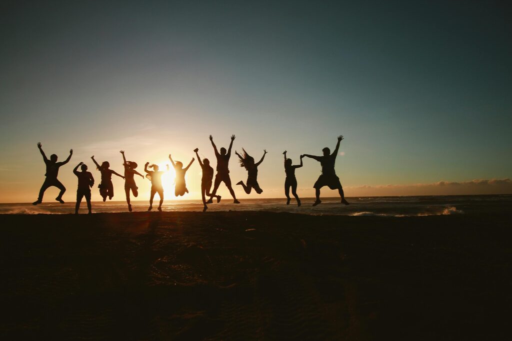 Silhouette of a team jumping in joy on the beach at sunset