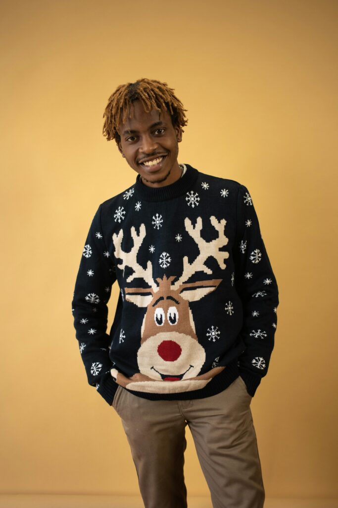 Smiling man wearing a Christmas sweater with a reindeer design.
