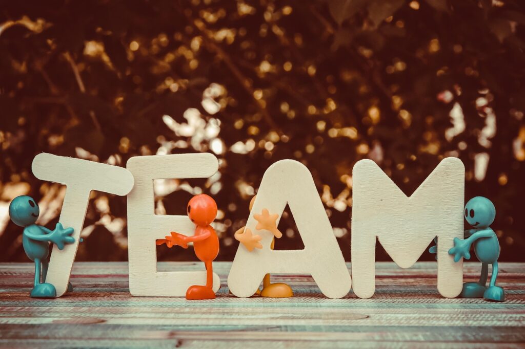 Colorful figurines holding up letters spelling "TEAM," symbolizing teamwork and collaboration