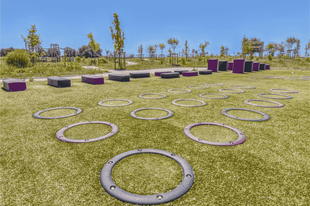 Outdoor obstacle course with rings and platforms on artificial grass.