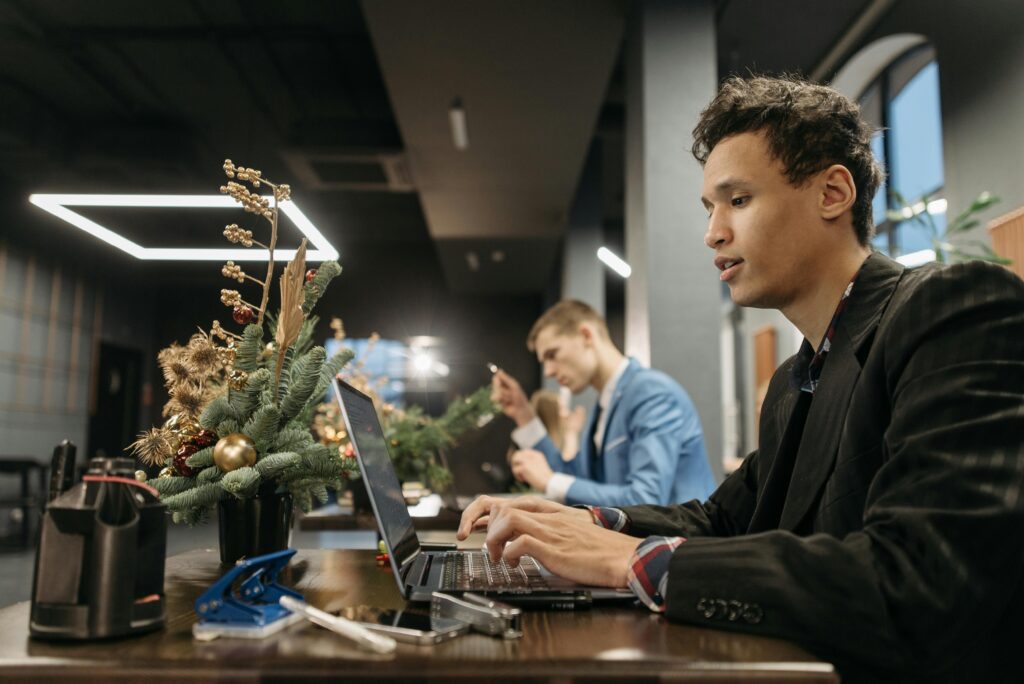 Man working on a laptop at an office desk decorated with holiday ornaments.