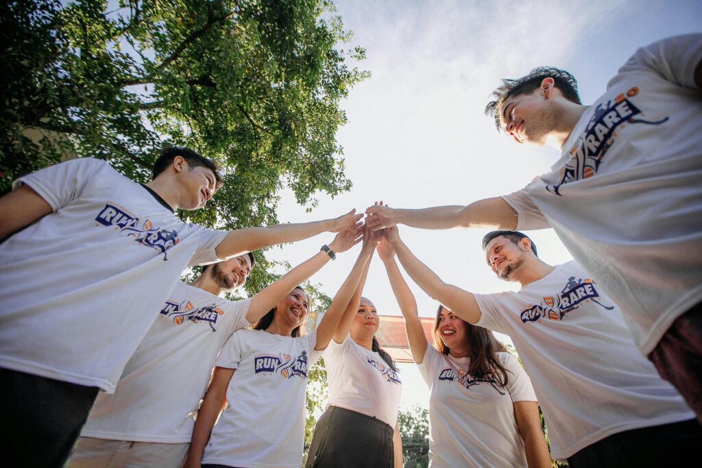 Group of people in matching shirts doing a team huddle outdoors.